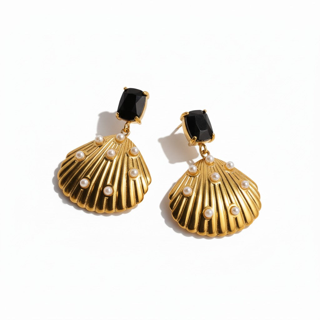 Gold shell-shaped earrings with black stones and pearl-like accents on a white background