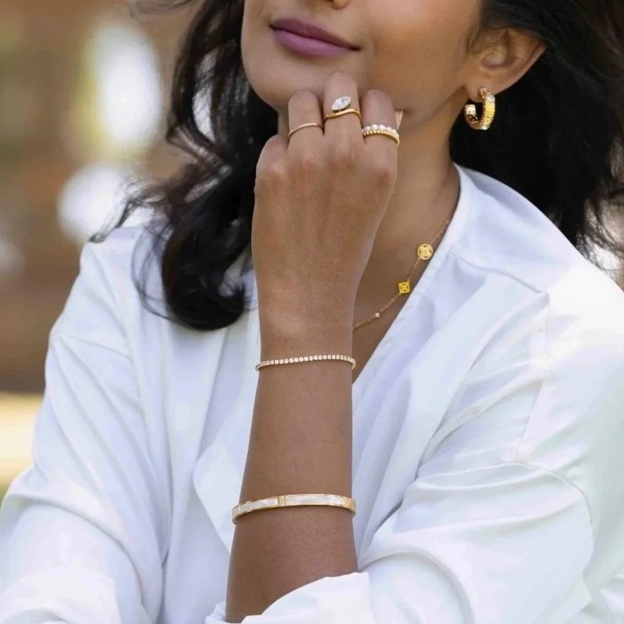 Woman wearing gold jewelry including rings, bracelets, and earrings.